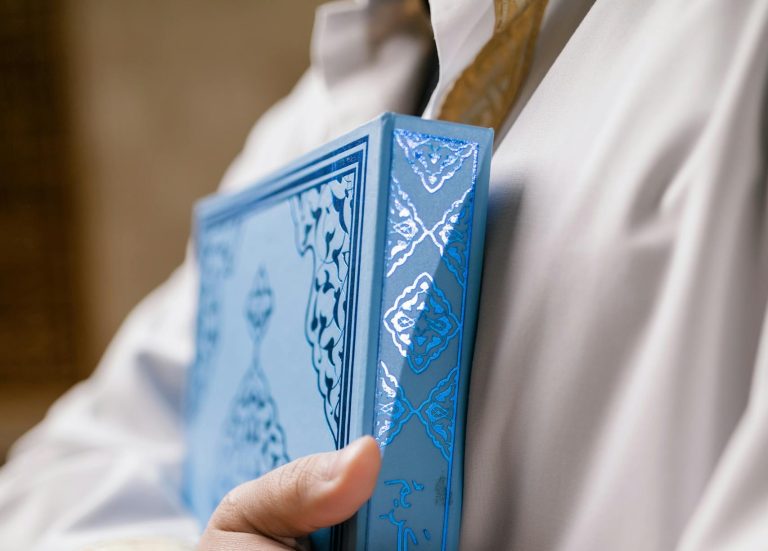 A close-up image showing hands holding a blue Quran, symbolizing faith.