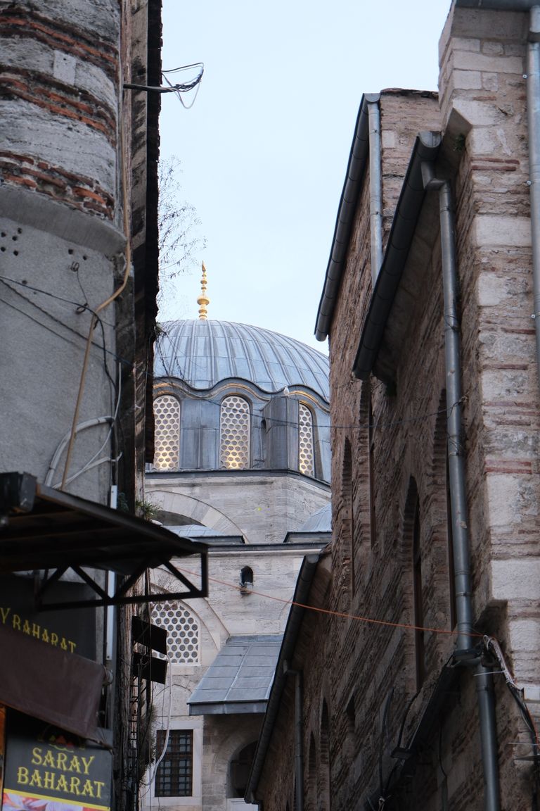 A glimpse of Istanbul's historic architecture with a mosque dome through narrow streets.