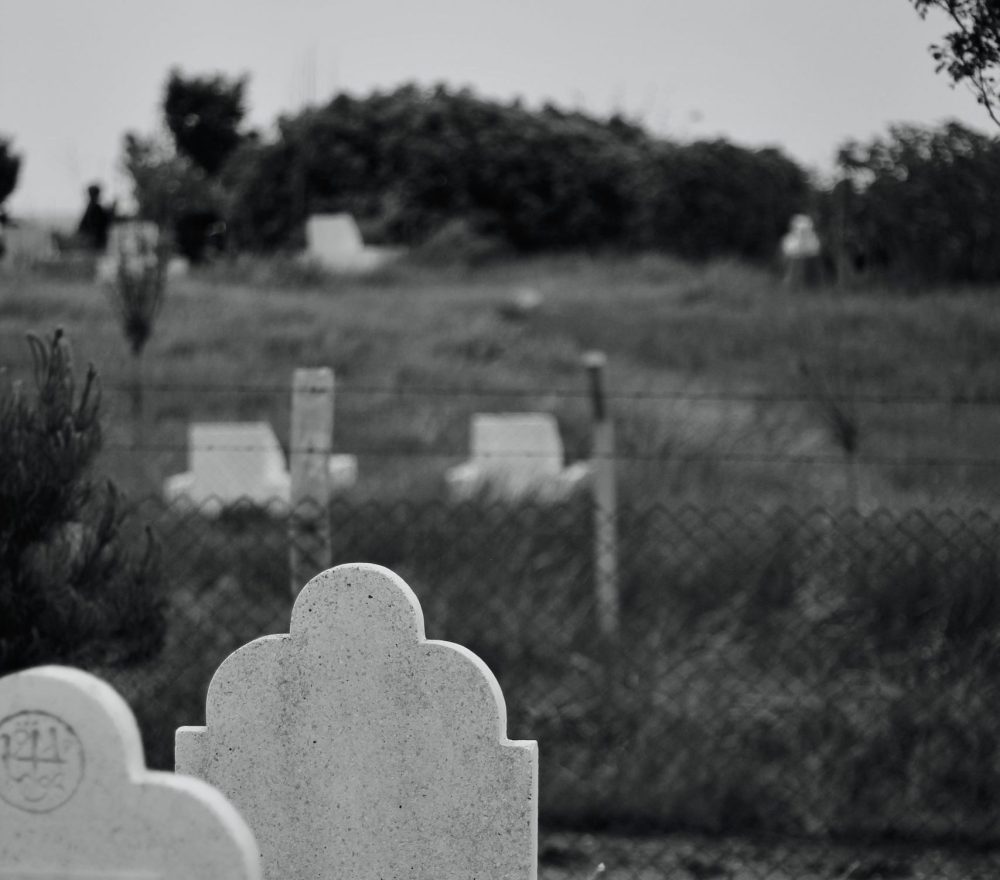 A serene black and white cemetery image featuring tombstones and a tranquil landscape.