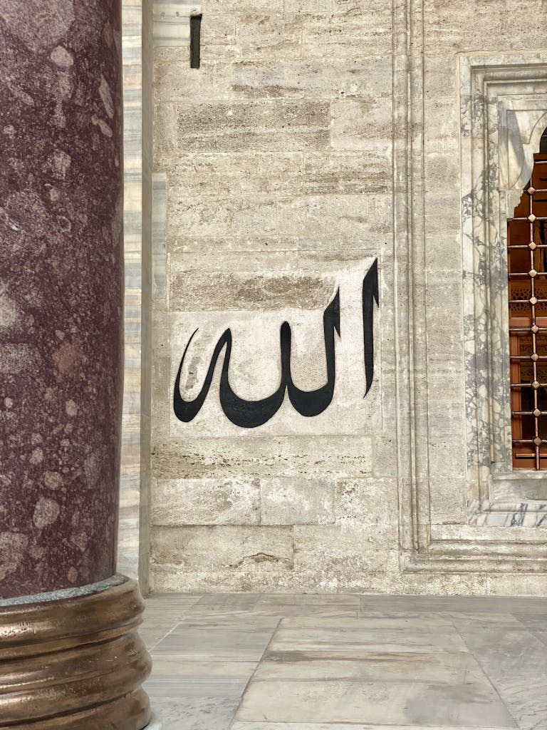 Arabic calligraphy on a historic stone wall with architectural elements.