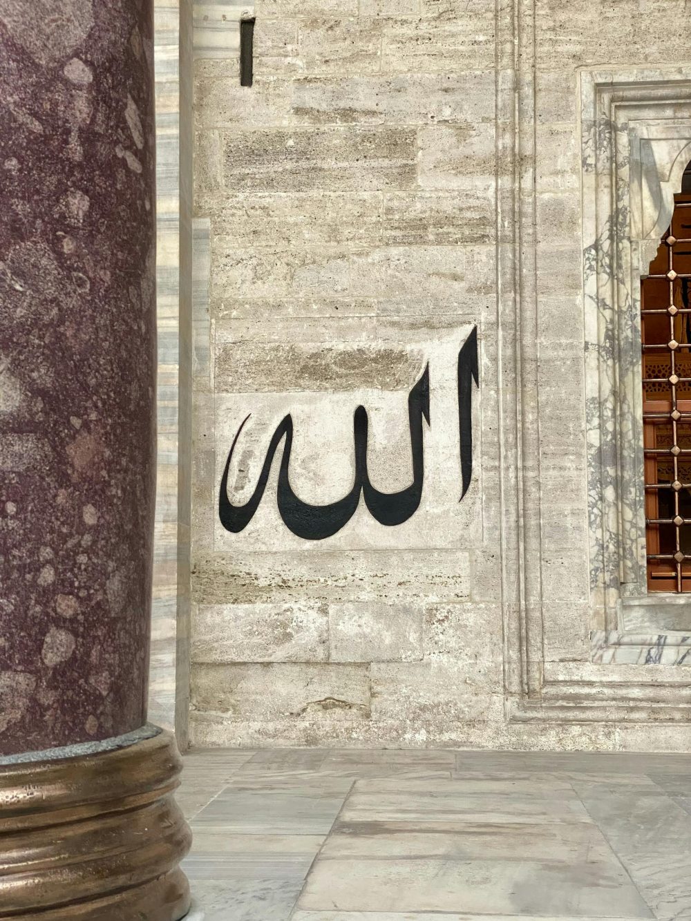 Arabic calligraphy on a historic stone wall with architectural elements.