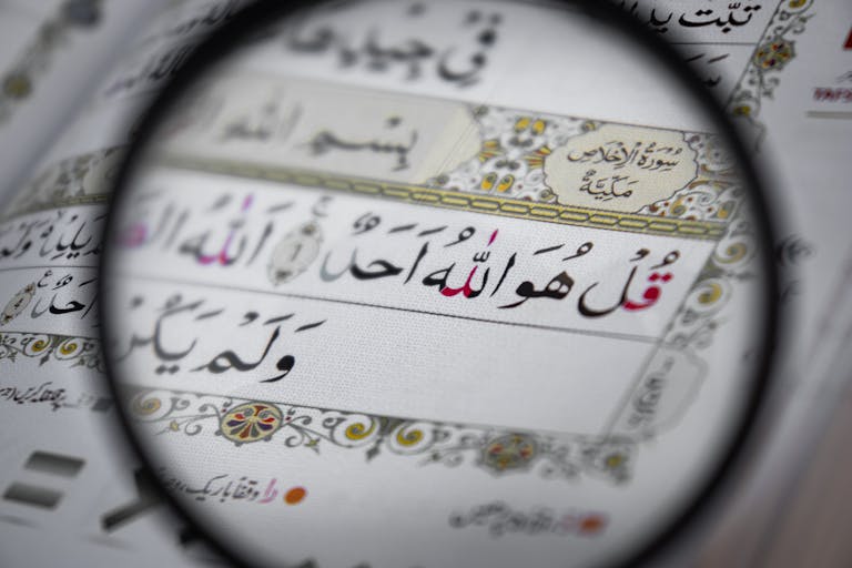 Detailed view of the Quran with intricate Arabic scripts, magnifying religious text and design.